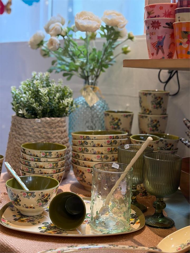 Vaisselle fleurie et verrerie verte présentées en boutique
